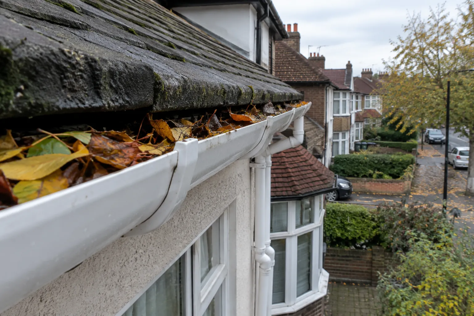 House gutter overflowing with autumn leaves
